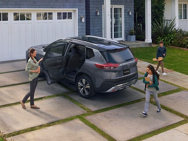 Una mujer con mucha actitud y estilo, cruza una calle mientras vemos una Nissan X-Trail estacionada al fondo